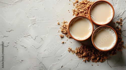 Three cups of chai with scattered cookie crumbs on a textured grey surface photo