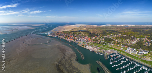 Aerial drone image of the historic Frisian town of West Terschelling on the Wad island in world heritage site Wadden Sea. Old brick lighthouse Brandaris and marina with dunes, sandbanks and tidal sea 