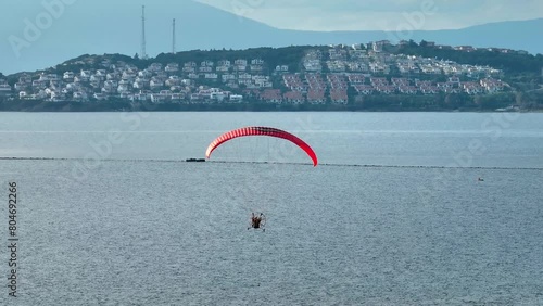 Close-up of a paramotor tricycle suspended under a parachute in the air. Drone shooting of man with paramotor flying in the air photo