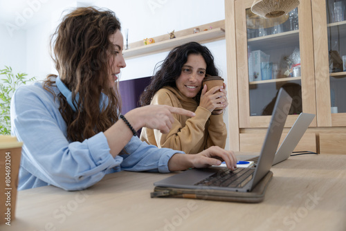 coworkers working at home and pointing the screen of their laptop