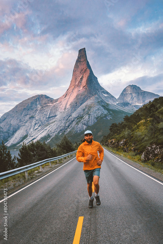 Man running in mountains asphalt road in Norway travel active healthy lifestyle outdoor adventure summer vacations motivation sport freedom concept Stetind peak view © EVERST
