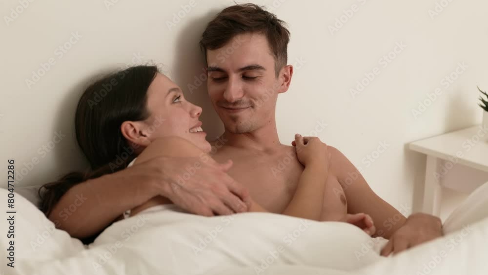 A loving couple cozily wrapped in a blanket, touching noses and sharing an intimate moment in the comfort of their bed. A loving couple cozily wrapped in a blanket, touching noses and sharing an intimate moment in the comfort of their bed.
