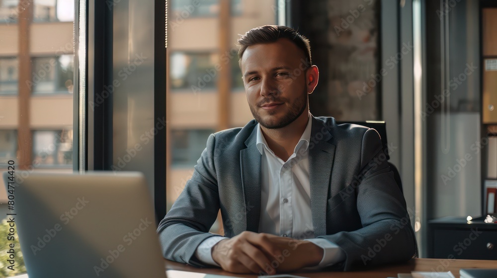 A professional businessman focused on his laptop in a modern office setting, conveying dedication A professional businessman focused on his laptop in a modern office setting, conveying dedication