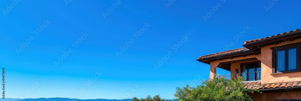 Corner perspective of an upscale house with terracotta tiles and clear blue sky, depicting affluence Corner perspective of an upscale house with terracotta tiles and clear blue sky, depicting affluence