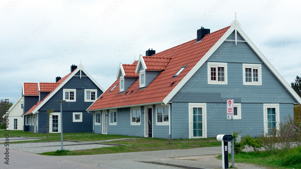 2024-04-23, Julianadorp aan Zee, Nordholland, Niederlande, Strandnahe Ferienhäuser in dem Landal Beach Resort Ooghduyne, Ansicht von vorne mit Gartenarbeiter