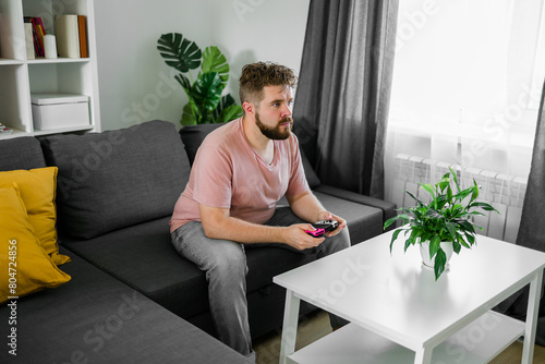 Man playing videogames in living room sitting on sofa.