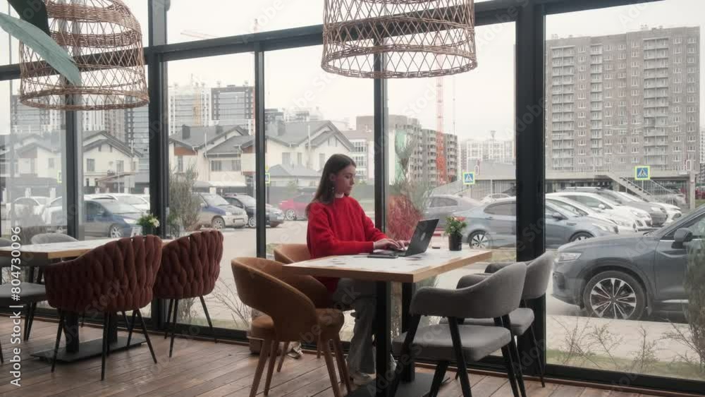 Portrait of a young girl who works as a freelancer on the veranda of a cafe. Computer work, Internet, remote work.