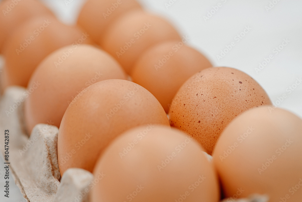 orange hen eggs lying in cardboard box, dozen eggs on white wooden background, selective focus orange hen eggs lying in cardboard box, dozen eggs on white wooden background, selective focus