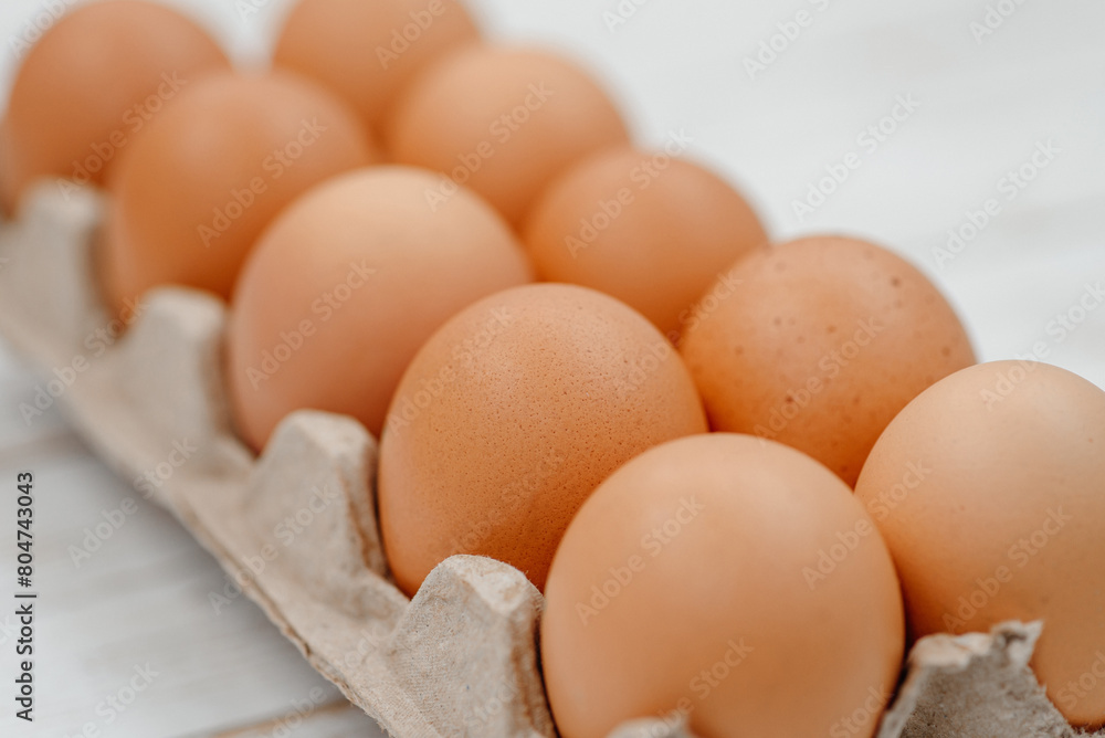 orange hen eggs lying in cardboard box, dozen eggs on white wooden background, selective focus orange hen eggs lying in cardboard box, dozen eggs on white wooden background, selective focus