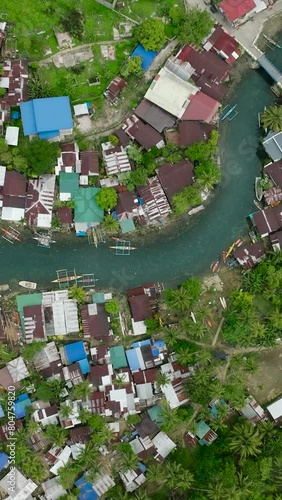 Houses and fishing boats along the Bogac Cold Spring in Surigao del Sur. Philippines. Vertical view. photo