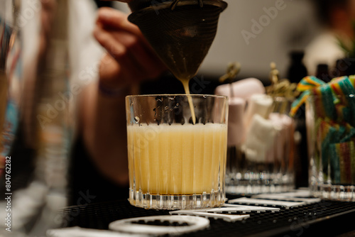 The bartender prepares a yellow cocktail.