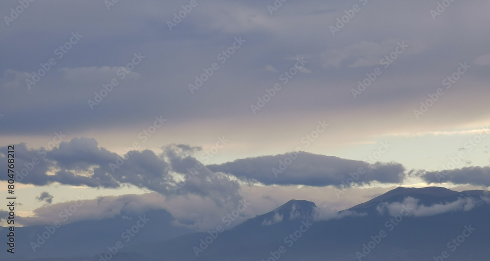 Nuvole bianche e grigie aggrappate come ovatta alle montagne in una giornata invernale al tramonto Nuvole bianche e grigie aggrappate come ovatta alle montagne in una giornata invernale al tramonto