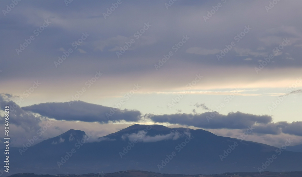 Nuvole bianche e grigie aggrappate come ovatta alle montagne in una giornata invernale al tramonto Nuvole bianche e grigie aggrappate come ovatta alle montagne in una giornata invernale al tramonto