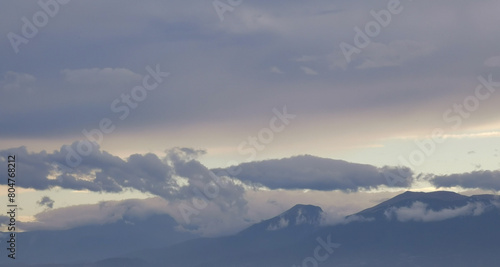 Nuvole bianche e grigie aggrappate come ovatta alle montagne in una giornata invernale al tramonto