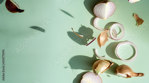 group of onions sit on a vibrant green surface, with a sliced onion falling from above onto the flat lay.