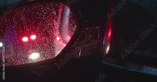 Police Lights Flashing In Drivers Side View Mirror. At Night In The Rain.