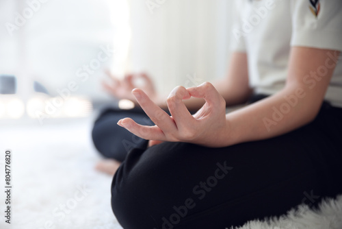 Close up image of woman's hands who was sitting cross-legged on the floor of the room at home To meditate to make the mind calm and relaxed. The room is bright with natural light.