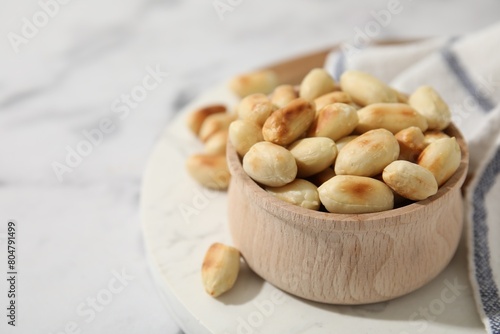 Roasted peanuts in bowl on white table, closeup. Space for text