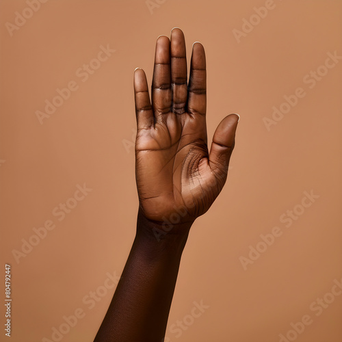 Close-up of a raised african-american hand against a warm neutral backdrop