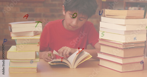 Digital composition of multiple alphabets floating against boy reading a book in library