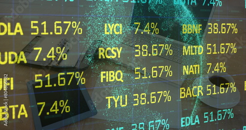 Digital composite image of stock market data processing against laptop and office equipment on desk