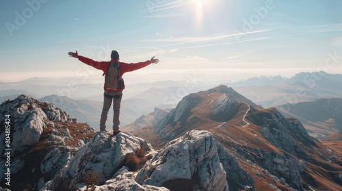 Mountain Majesty: Man on Summit with Arms Aloft, Embracing the Splendor of the Peaks.