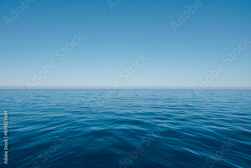 A vast expanse of deep blue sea, with the horizon line stretching across an endless sky of clear and unbroken light blue color, ripples
