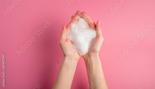 Hands disinfection during coronovirus concept. Female hands with soap foam on a pink background photo