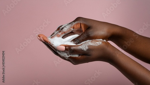 Hands disinfection during coronovirus concept. Female hands with soap foam on a pink background photo