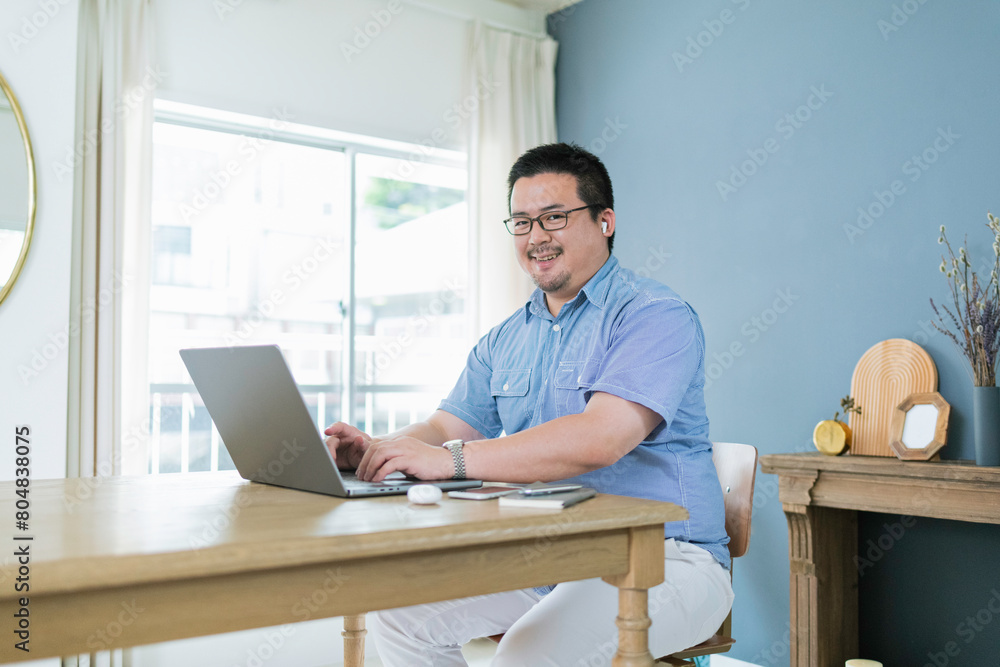 自宅でリモートワークをする大柄な日本人男性 自宅でリモートワークをする大柄な日本人男性