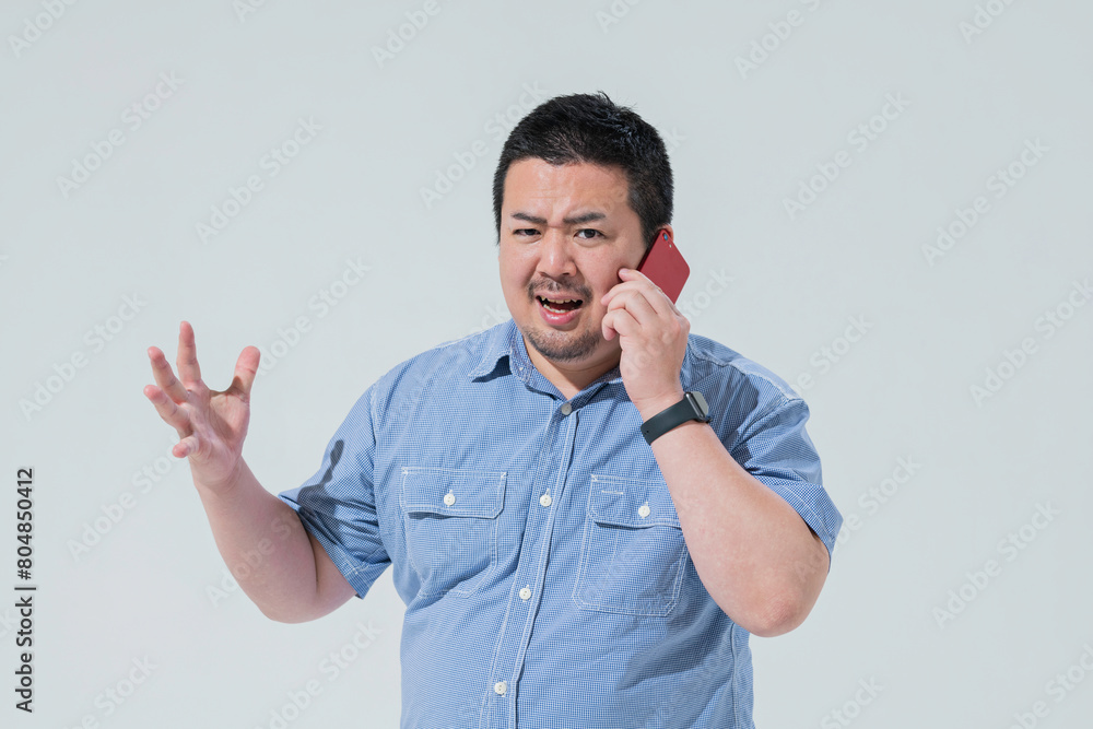 電話をしながら感情的になる大柄な日本人男性 電話をしながら感情的になる大柄な日本人男性