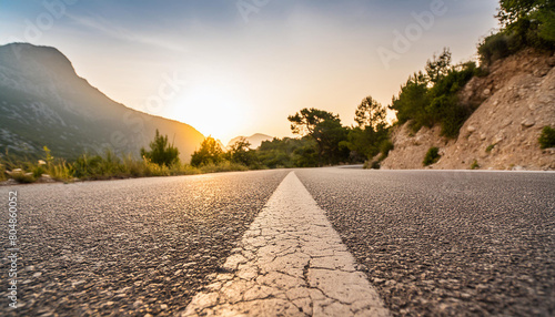 Low level view of empty old paved road in mountain area at sunset; blue cloudy sky; travel concept