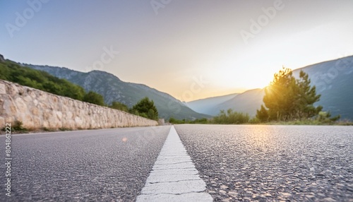 Low level view of empty old paved road in mountain area at sunset; blue cloudy sky; travel concept