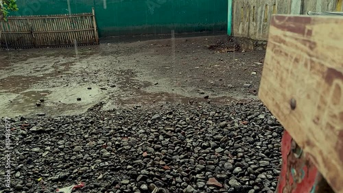 The view of drizzling rain in front of the house decorated with rocks