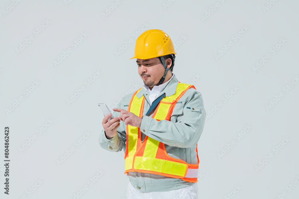 スマートフォンを使う作業服の男性 スマートフォンを使う作業服の男性