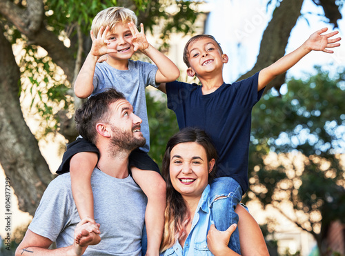 Portrait, park and parents with children on shoulder for fun outdoor bonding, vacation adventure and smile. Mother, father and excited kids in garden for happy family on holiday together in summer.
