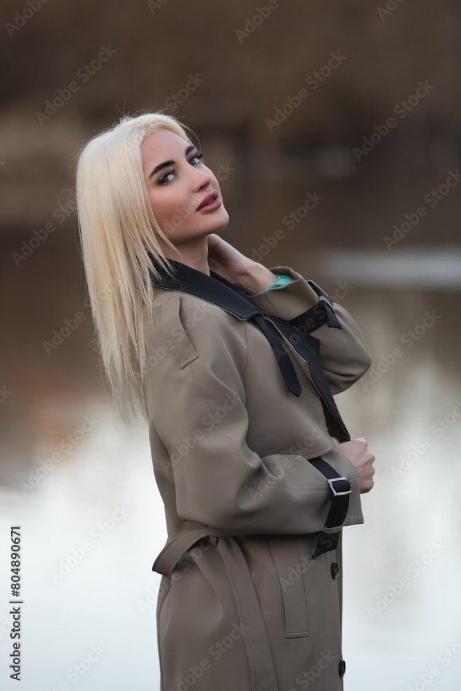 Portrait of a young beautiful blonde girl in a raincoat in the park. Portrait of a young beautiful blonde girl in a raincoat in the park.