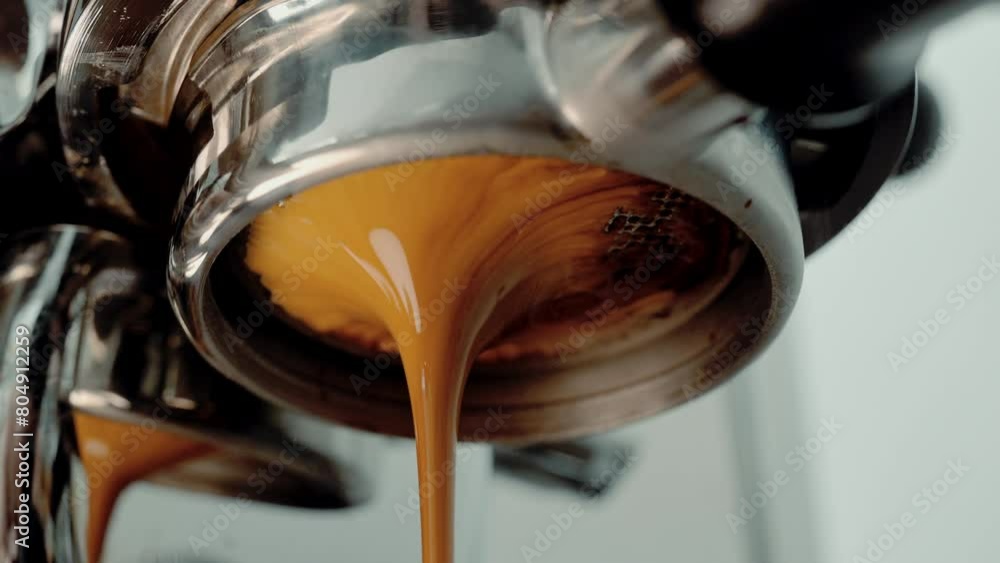 4K Pouring coffee stream from professional machine in cup. Barista man making double espresso, using filter holder. Flowing fresh ground coffee. Drinking roasted black coffee in the morning.