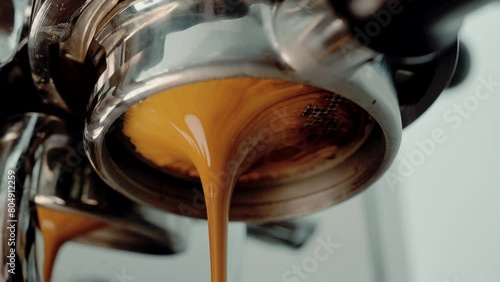 4K Pouring coffee stream from professional machine in cup. Barista man making double espresso, using filter holder. Flowing fresh ground coffee. Drinking roasted black coffee in the morning.