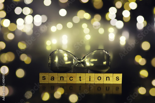 word sanctions spelled in letters on table made of wooden block letters with dramatic lighting and smoke