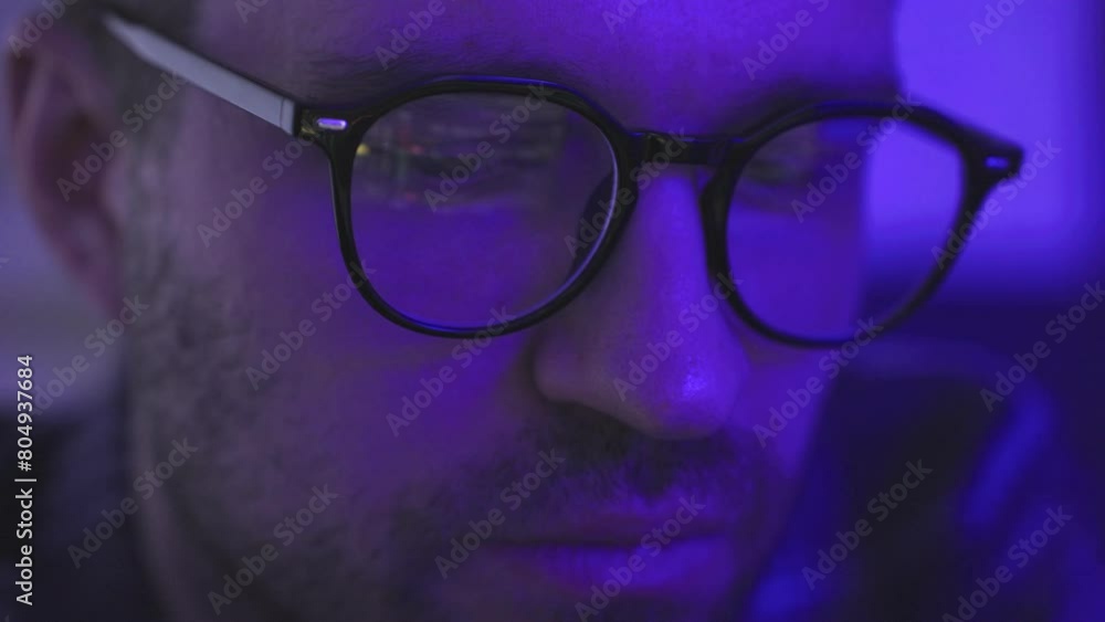 Young man in glasses checking rate of cryptocurrency, looking on gadget screen Young man in glasses checking rate of cryptocurrency, looking on gadget screen