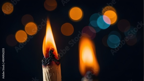 Low-key, close-up of a burning matchstick against a bokeh-style black background