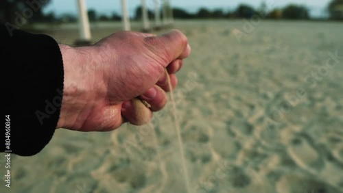 The hand takes the sand and pours it out, slow motion. Tick tock time, beach vacation, passing time concept. Travel, relaxation and serenity. Summer vacation and tourism concept. Go Everywhere photo