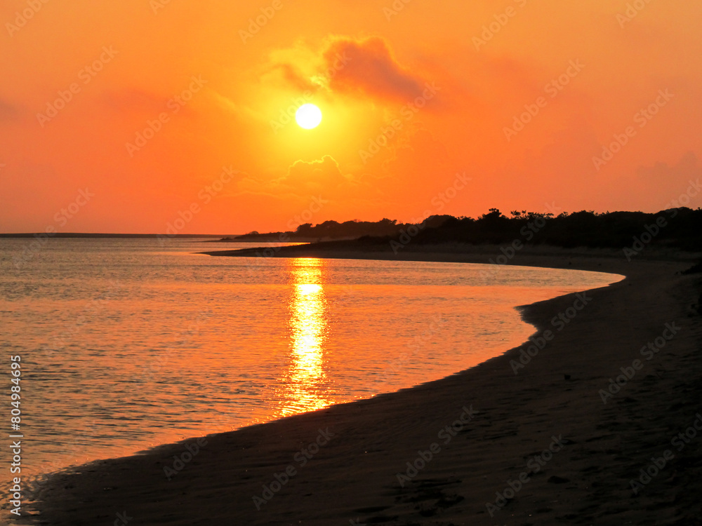A golden sunrise, with the sun reflecting in a small secluded bay at the Portuguese islands along the southern coast of Mozambique in Southern Africa.
