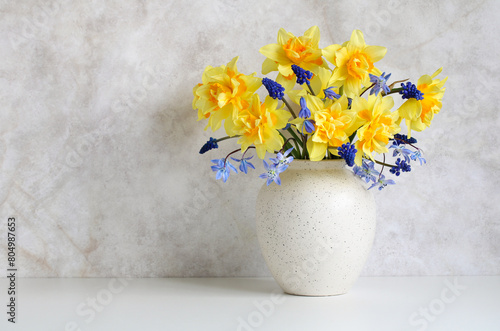 garden daffodils and hyacinths, spring flowers in a potbellied vase on a light background. copy space. photo