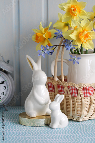 Easter bunnies on the table in close-up, a bouquet of yellow daffodils.