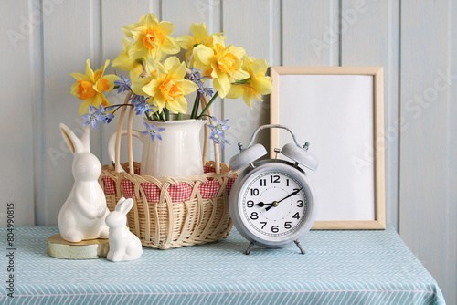 Easter composition with a bouquet of daffodils and Easter bunnies on the table.