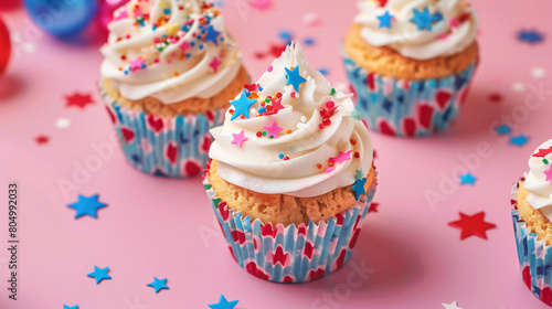 Tasty patriotic cupcakes with flags of USA on pink background