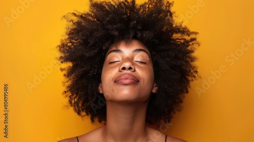 Upbeat woman with afro hair looking upwards on a neutral background photo