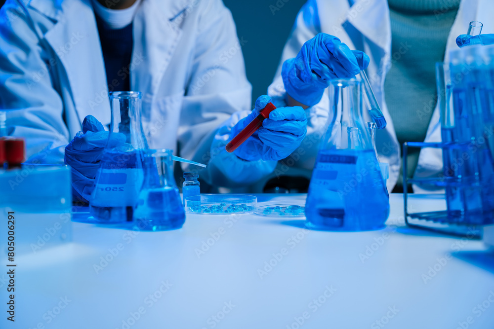 Fototapeta premium Medical or research scientist or doctor using looking at a test tube of clear solution in a lab or laboratory.